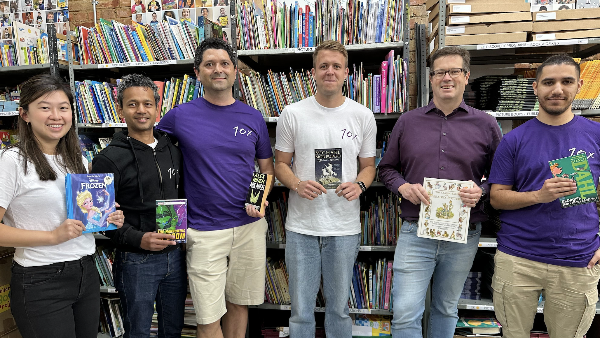 Adele and the client team hold books at the Children's Book Project